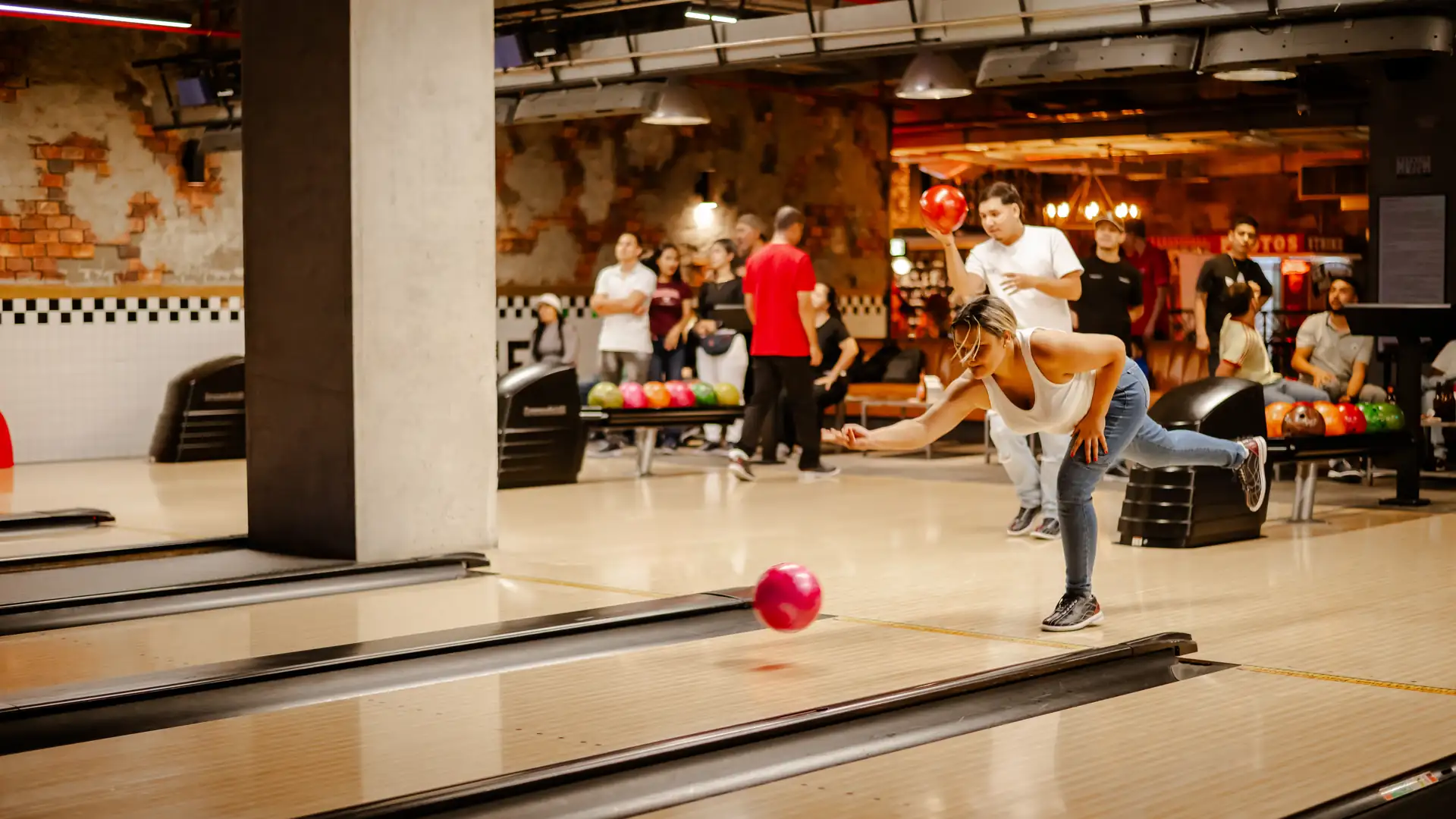 Una jugadora lanza la bola por la pista de bolos